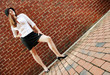 Fashionable young woman posing in front of a brick wall.
