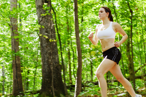 Photo: Beautiful young woman runner in a green forest. Beautiful young woman runner in a green forest.