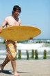 Skimboarder walking along the beach. Skimboarder walking along the beach.