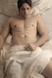 Photo: young naked man in bed with white sheets young naked man in bed with white sheets
