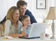 Mother and Father using a laptop with their daughter Mother and Father using a laptop with their daughter