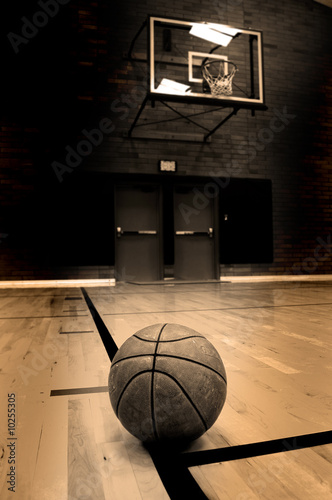 Photo: Basketball on court with hoop in the background Basketball on court with hoop in the background