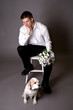 Thoughtful groom in thoughtful post with a dog at his feet.