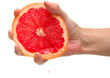 The female hand squeezes out juice from a ripe grapefruit.