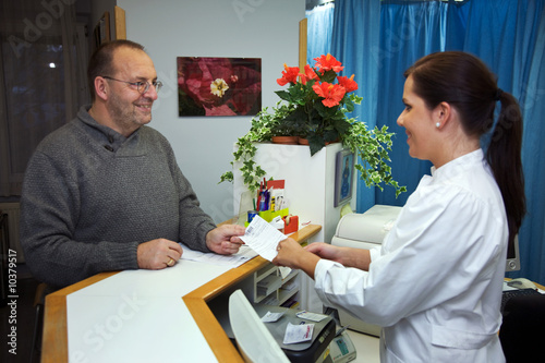 Foto: Patient bekommt ein Rezept von der Arzthelferin Patient bekommt ein Rezept von der Arzthelferin