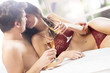 Couple kissing and drinking on the bed in bedroom