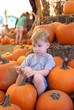 Young boy resting in a pile of pumpkins after a long day at play