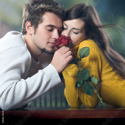 Photo: Young couple with rose, outdoors Young couple with rose, outdoors