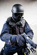 The armed soldier in a camouflage costs in alertness on a gray The armed soldier in a camouflage costs in alertness on a gray