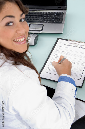 Photo: smiling doctor holding pen and looking at camera against smiling doctor holding pen and looking at camera against