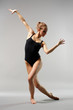 young and beautiful ballerina posing on grey background
