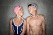 Senior couple in changing room, wearing swim cap and goggles