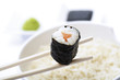 Maki Sushi with chopsticks above bowl of rice, close-up