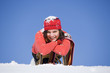Woman covered with snow lying on sledge, smiling