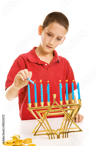 Young boy lighting the menorah for Hanukkah.  Isolated