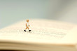 Foto: Figurine of boy walking on open book, close-up Figurine of boy walking on open book, close-up