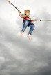 Boy (10-11) on bungee swing, smiling, low angle view