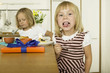 Two little girls (4-5) eating cake in kitchen