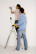 Young couple, man holding electric drill, woman measuring wall with scale