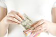 Photo: Woman putting Dollar notes in change purse, close-up Woman putting Dollar notes in change purse, close-up