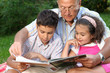 Grandfather,grandson and granddaughter reading a book