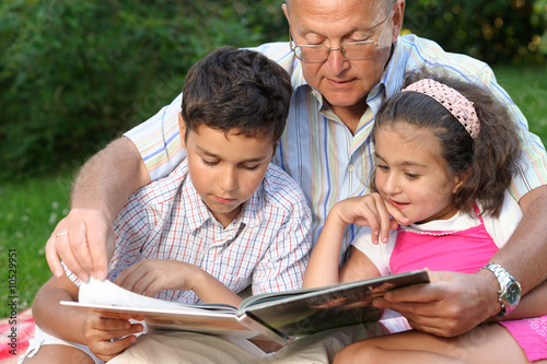 Photo: Grandfather,grandson and granddaughter reading a book Grandfather,grandson and granddaughter reading a book