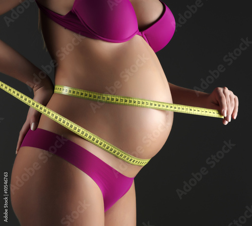 pregnant woman measures her belly.