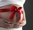 A bow on a belly of a pregnant woman