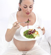 Pregnant woman in bed eating salad
