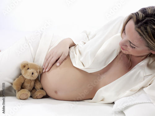 Photo: pregnant with bear in bed on a white background pregnant with bear in bed on a white background