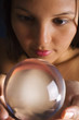 A young Asian woman looks into a crystal ball A young Asian woman looks into a crystal ball