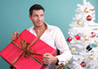 Unterm Weihnachtsbaum Mann packt Geschenk aus