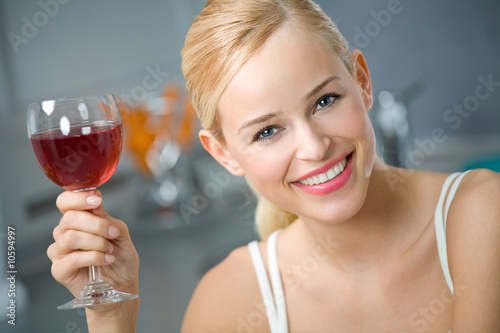 Photo: Young woman with red wine at kitchen Young woman with red wine at kitchen