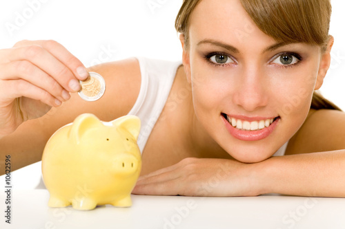 Foto: Woman putting coin in piggy bank Woman putting coin in piggy bank