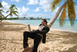 business au soleil - homme allongé sur un cocotier avec son ordi business au soleil - homme allongé sur un cocotier avec son ordi