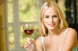 Portrait of young woman with red-wine glass, indoors