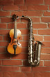 Violin & saxophone over red brick wall