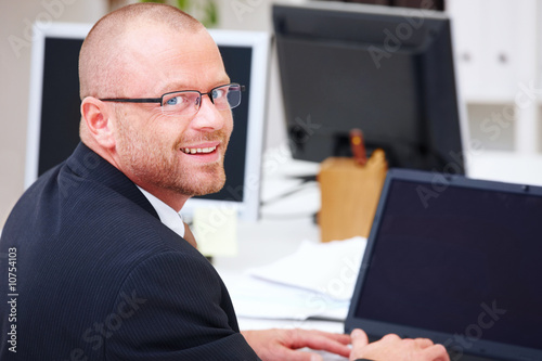 Office life - Happy businessman using a laptop Office life - Happy businessman using a laptop