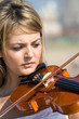 young blond woman play violin on beach