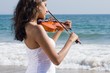 young indian woman play violin on beach