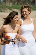 happy female friends walking on beach
