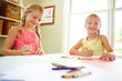 Photo: Smiling girls sitting by table and drawing Smiling girls sitting by table and drawing