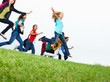 Young girls and boys jumping on the ground raising hands