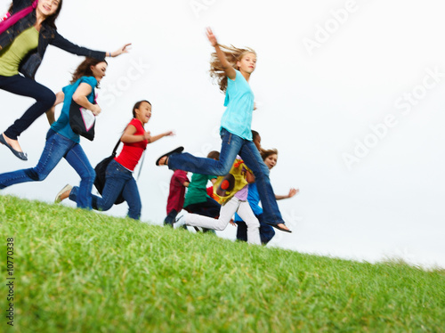 Photo: Young girls and boys jumping on the ground raising hands Young girls and boys jumping on the ground raising hands