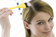 Portrait of a young woman dyeing her hair, little brush in her hand