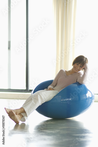Photo: Young woman resting in blue armchair, smiling for the camera Young woman resting in blue armchair, smiling for the camera