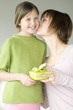 Woman holding present, kissing little girl on her cheek