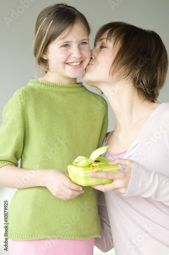 Photo: Woman holding present, kissing little girl on her cheek Woman holding present, kissing little girl on her cheek