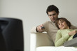 Couple lying on a sofa, watching TV