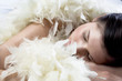 Foto: Young woman sleeping with white feather boa Young woman sleeping with white feather boa